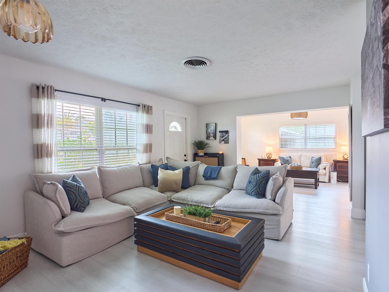 A living room features a large beige sectional sofa, a tiered coffee table, and light flooring — 3743 NE Barbara Drive, Jensen Beach FL 34957, JENSEN BEACH, FL