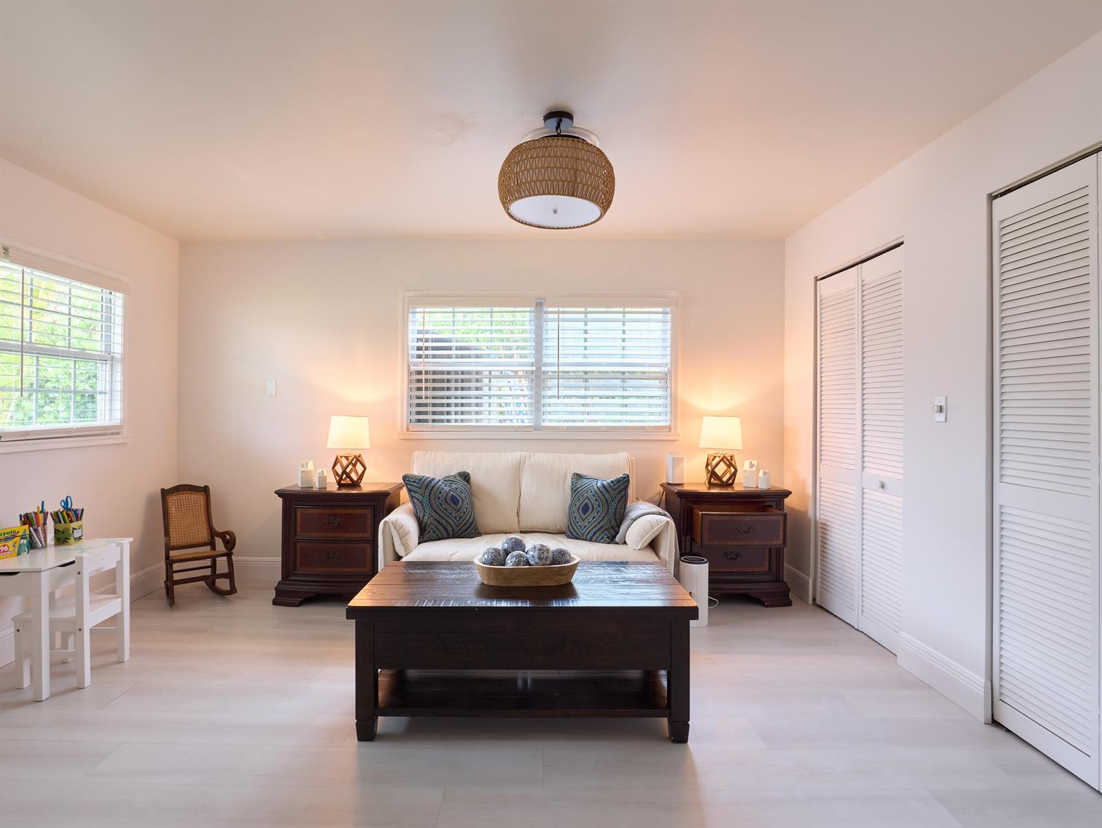 A living room features a white sofa, dark wood furniture, and a woven light fixture — 3743 NE Barbara Drive, Jensen Beach FL 34957, JENSEN BEACH, FL