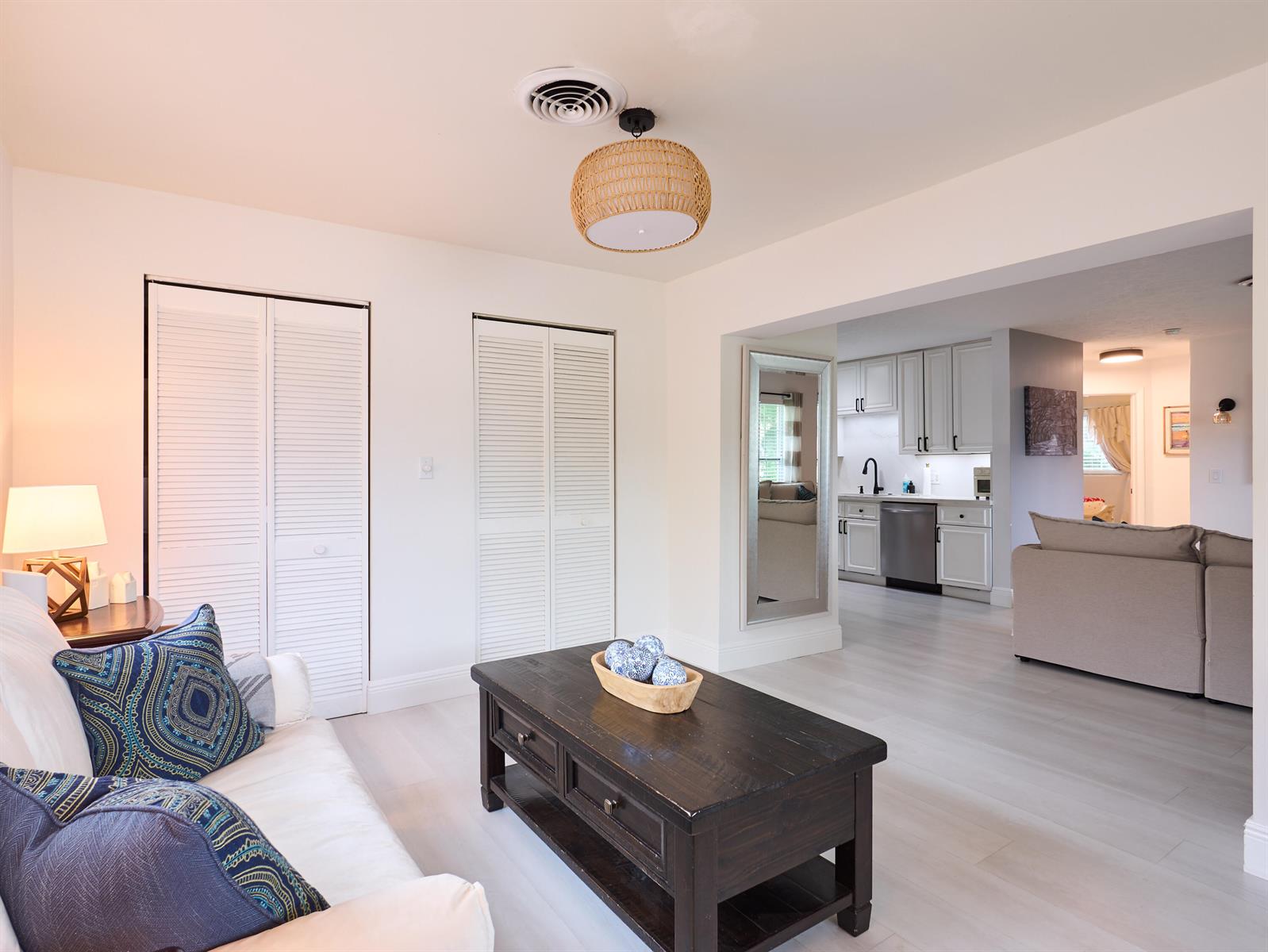 A living room with white walls and louvered closet doors opens into a kitchen area — 3743 NE Barbara Drive, Jensen Beach FL 34957, JENSEN BEACH, FL