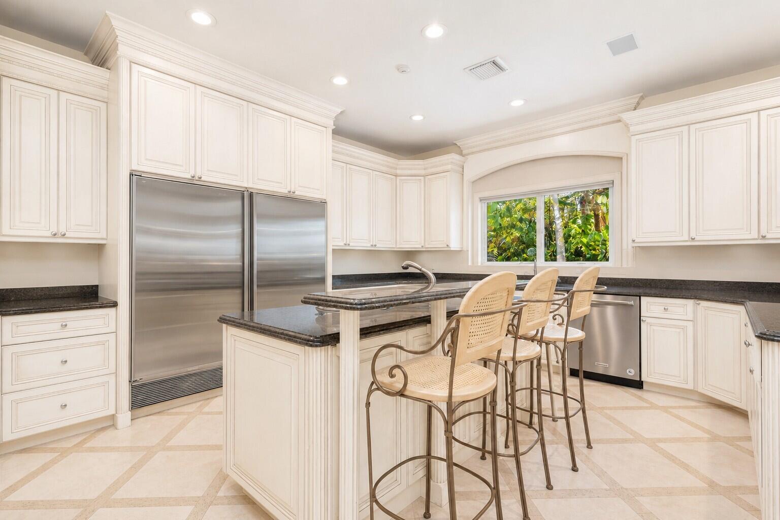 A kitchen with cream cabinets, stainless steel appliances, a granite island, and light tile flooring — 286 Jamaica Lane, Palm Beach FL 33480, PALM BEACH, FL