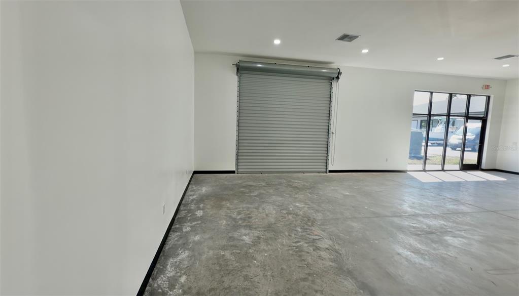 An interior view of a commercial space with a concrete floor and roll-up door — 727 TILLMAN PLACE UNIT 101, PLANT CITY, FL