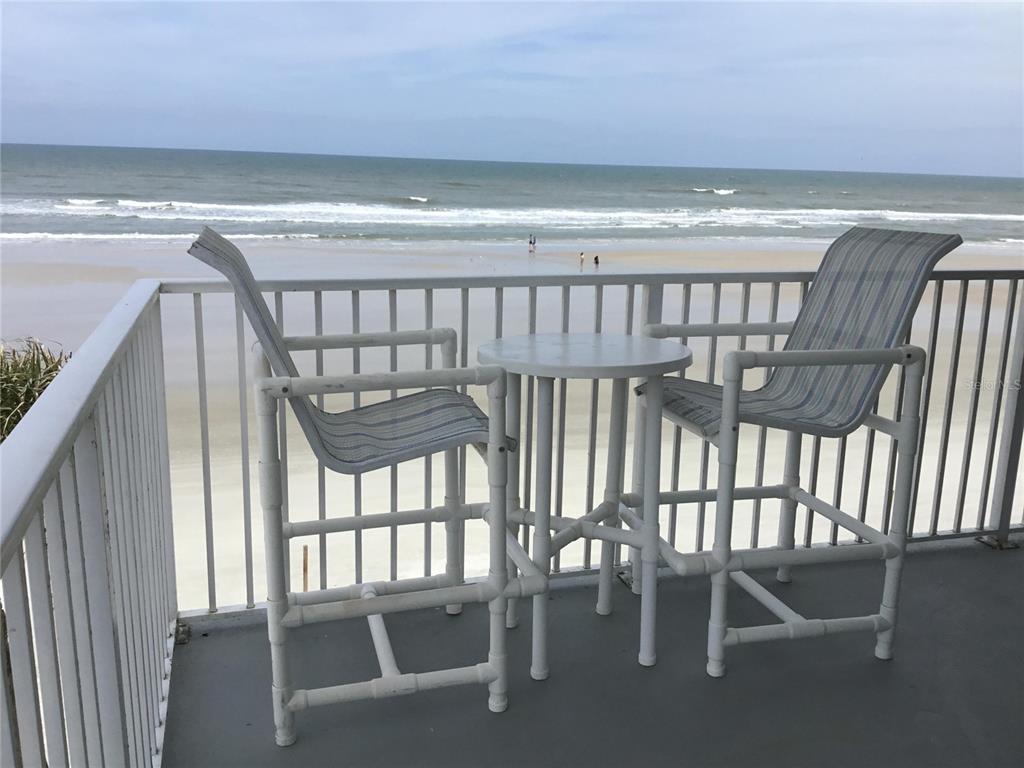 A balcony features two tall chairs and a small table overlooking a sandy beach — 1571 S ATLANTIC AVENUE UNIT 310, NEW SMYRNA BEACH, FL