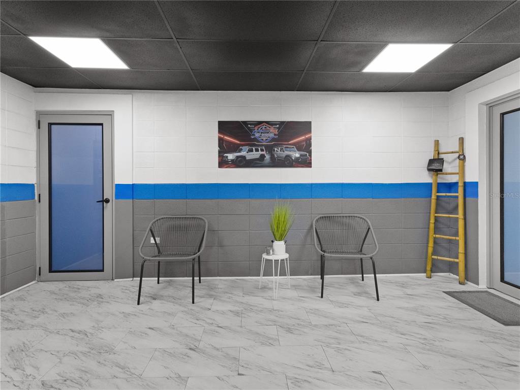 A waiting area features two chairs, a small table, and a wall-mounted car print — 1195 DEL CARMEN STREET, SAN JUAN, PR