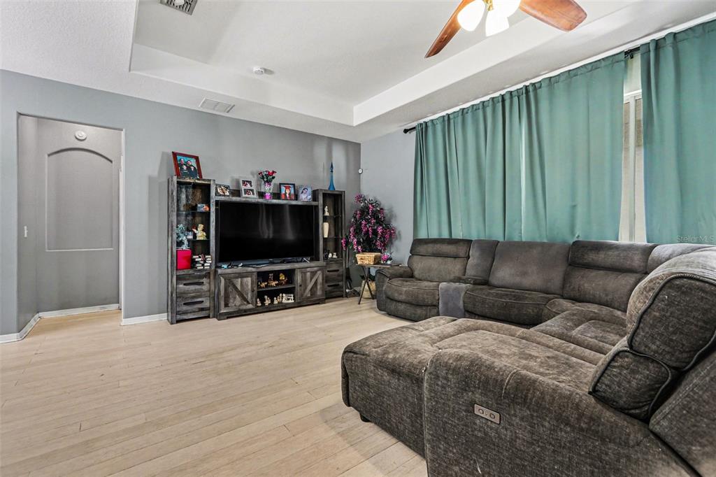 A living room features light wood flooring, a tray ceiling, a ceiling fan, and sliding doors — 2130 ROANOKE SPRINGS DRIVE, RUSKIN, FL