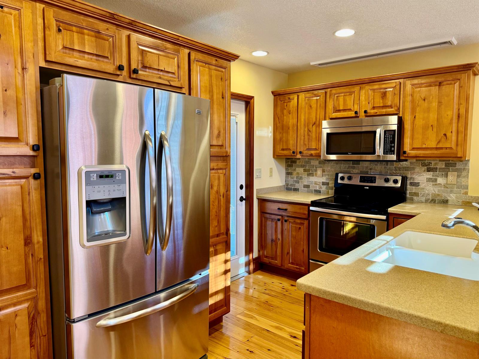 A kitchen with wood cabinets, stainless steel appliances, a stone backsplash, and light countertops — 4334 Us Highway 441 Highway SE # 23, Okeechobee FL 34974, OKEECHOBEE, FL