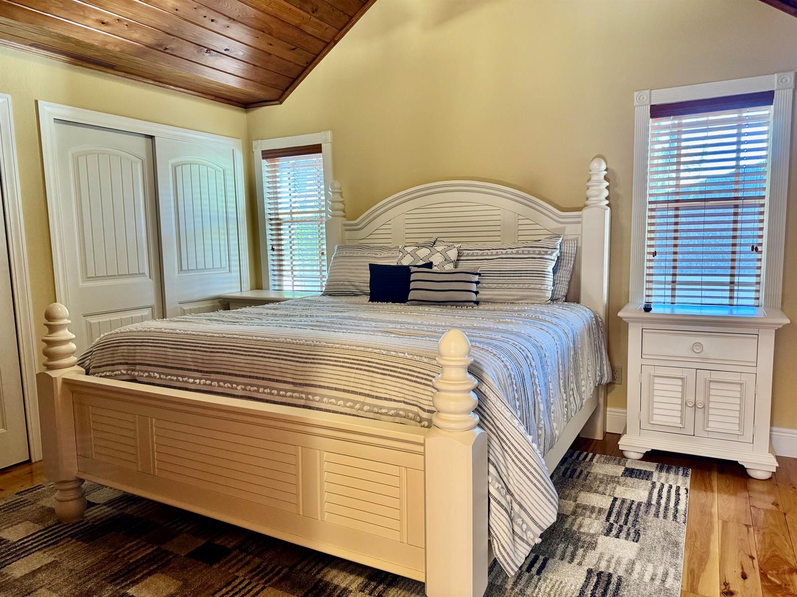A bedroom features a white wooden bed frame, striped bedding, and a vaulted wood ceiling — 4334 Us Highway 441 Highway SE # 23, Okeechobee FL 34974, OKEECHOBEE, FL