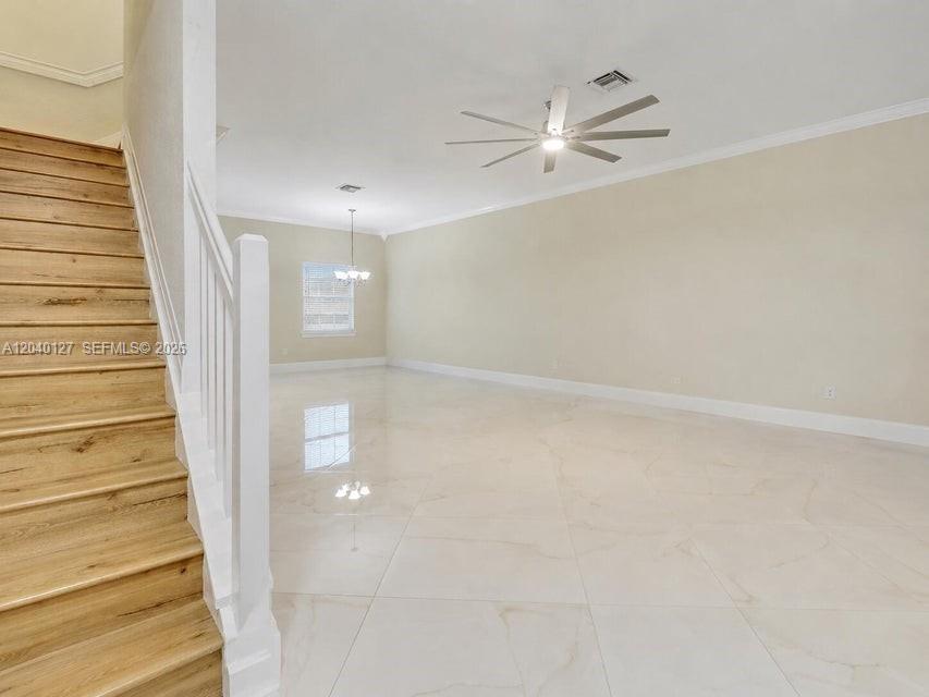 An empty room features light-colored tile flooring, a wooden staircase, and a ceiling fan — 118 Seagrape Dr # 105, Jupiter FL 33458, JUPITER, FL