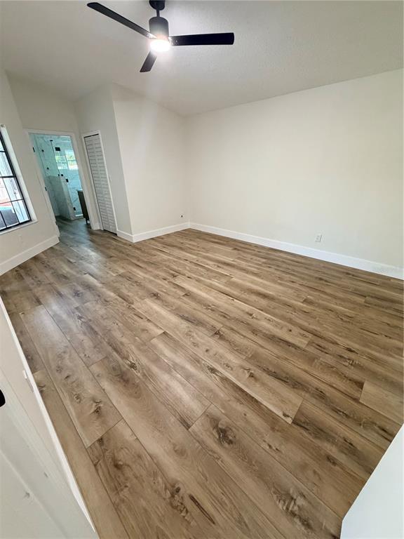 An empty bedroom features light wood-look flooring, white walls, a ceiling fan, and a closet — 2943 WOOLRIDGE DRIVE, ORLANDO, FL