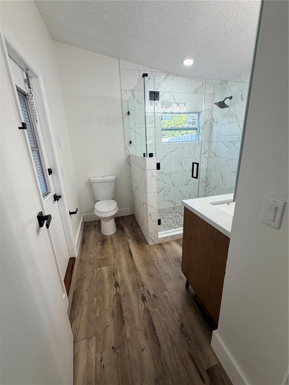 A bathroom features wood-look flooring, a white toilet, a marble-tiled walk-in shower, and a vanity — 2943 WOOLRIDGE DRIVE, ORLANDO, FL