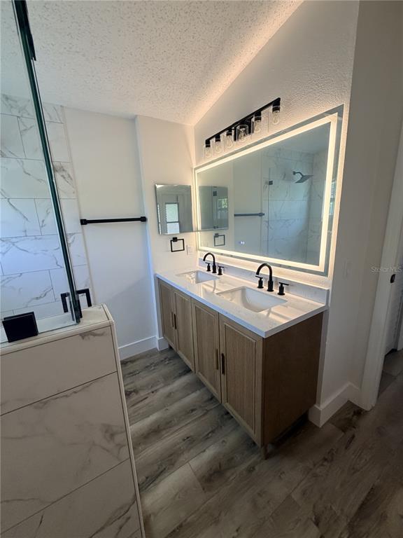 A modern bathroom features a double vanity with wood cabinets, white countertops, and a backlit mirror — 2943 WOOLRIDGE DRIVE, ORLANDO, FL