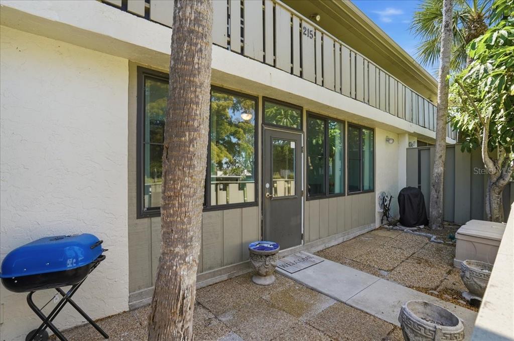 The exterior of a two-story building features a patio, a blue grill, and a doorway — 6500 FLOTILLA DRIVE UNIT 212, HOLMES BEACH, FL