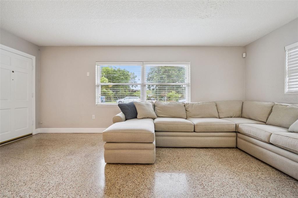 A living room features a large sectional sofa, a white hutch, and speckled terrazzo flooring — 2513 MUSSELWHITE AVENUE, ORLANDO, FL