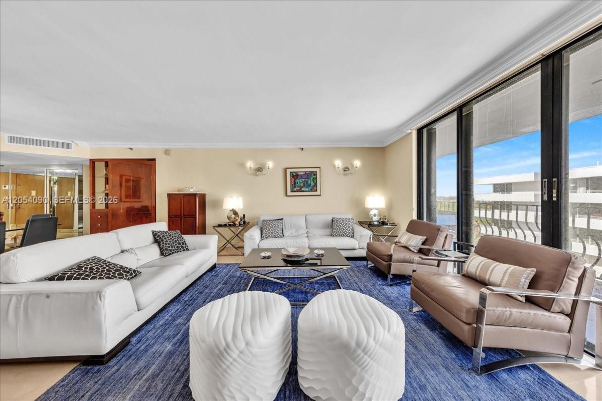 A living room features a blue rug, white sofas, brown armchairs, and floor-to-ceiling windows — 8877 Collins Ave # 2, Surfside FL 33154, SURFSIDE, FL