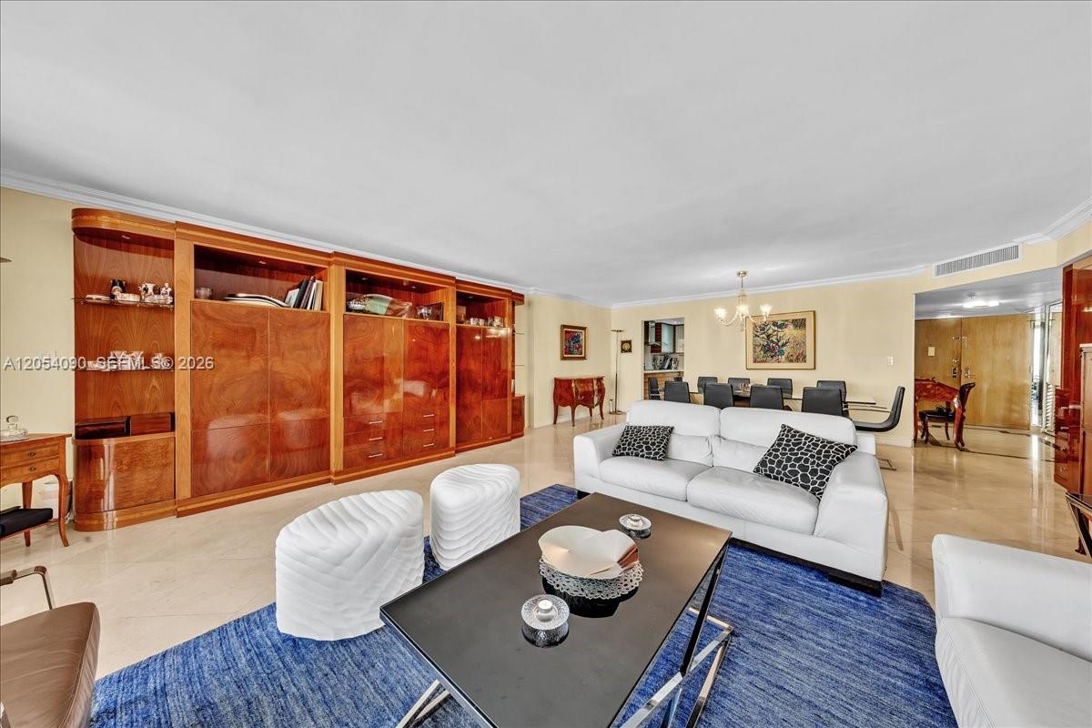 A living room features a large wood wall unit, white sofas, and a blue rug — 8877 Collins Ave # 2, Surfside FL 33154, SURFSIDE, FL