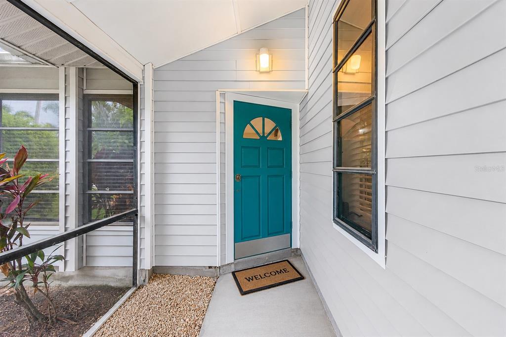 A teal front door with a window sits under a porch with light siding — 4903 SW 11TH PLACE, CAPE CORAL, FL