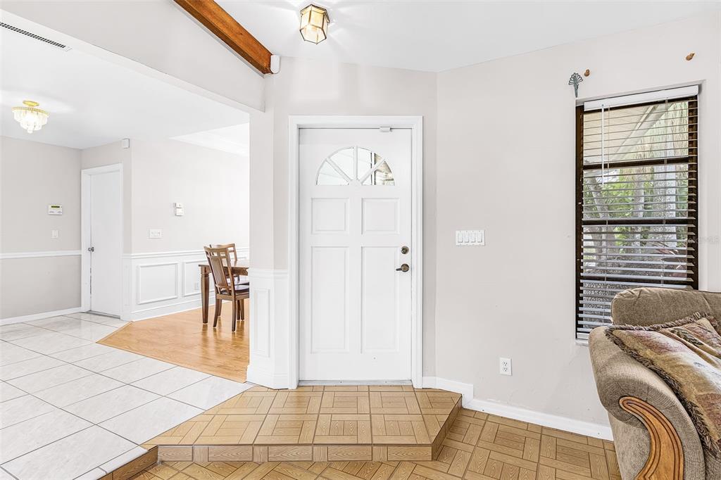 An entryway features a white front door, tiled flooring, and a view into a dining area — 4903 SW 11TH PLACE, CAPE CORAL, FL