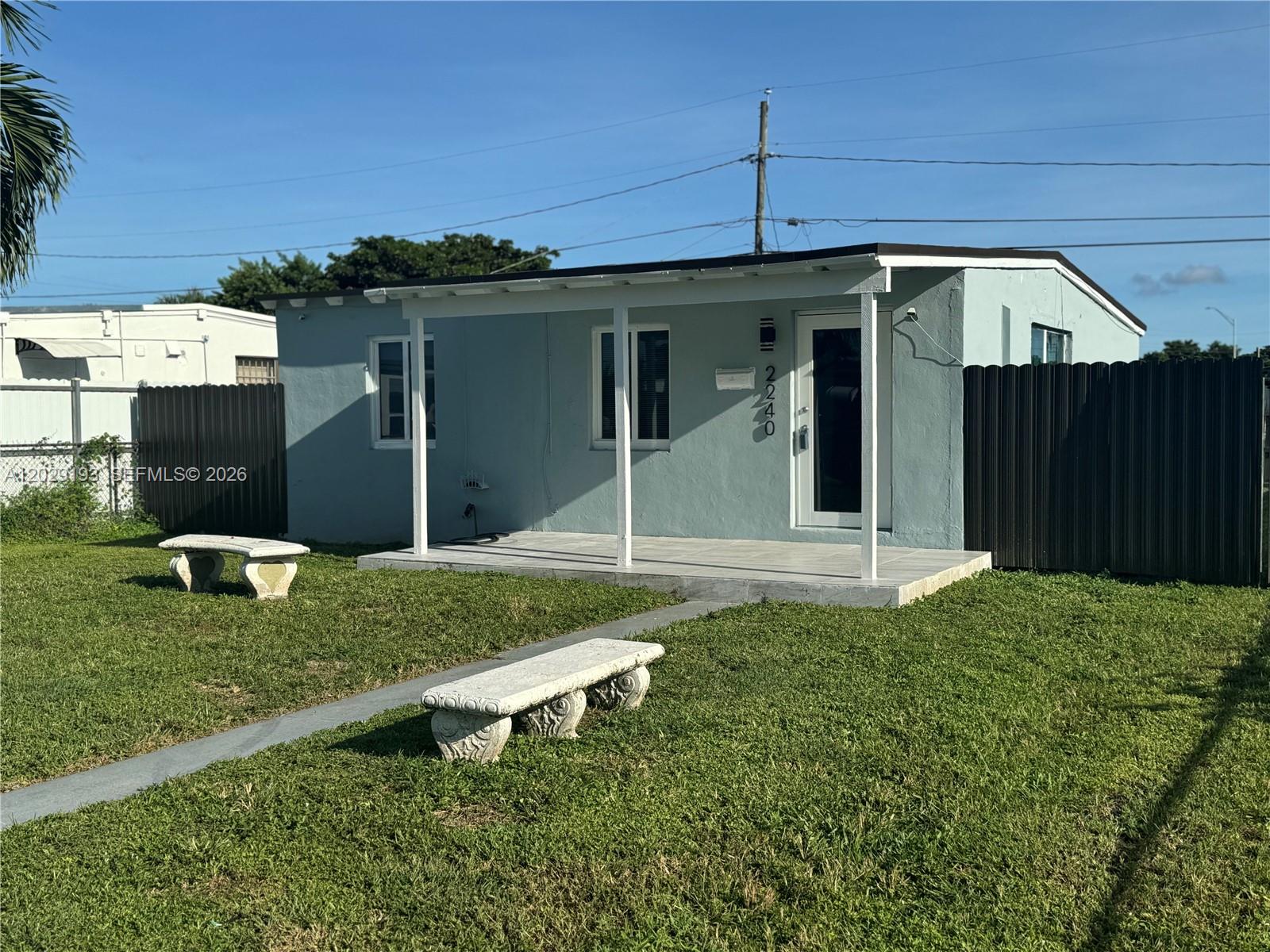 A light blue single-story house features a covered front porch and two stone benches — 2240 Rutland St # 0, Opa-Locka FL 33054, OPA-LOCKA, FL