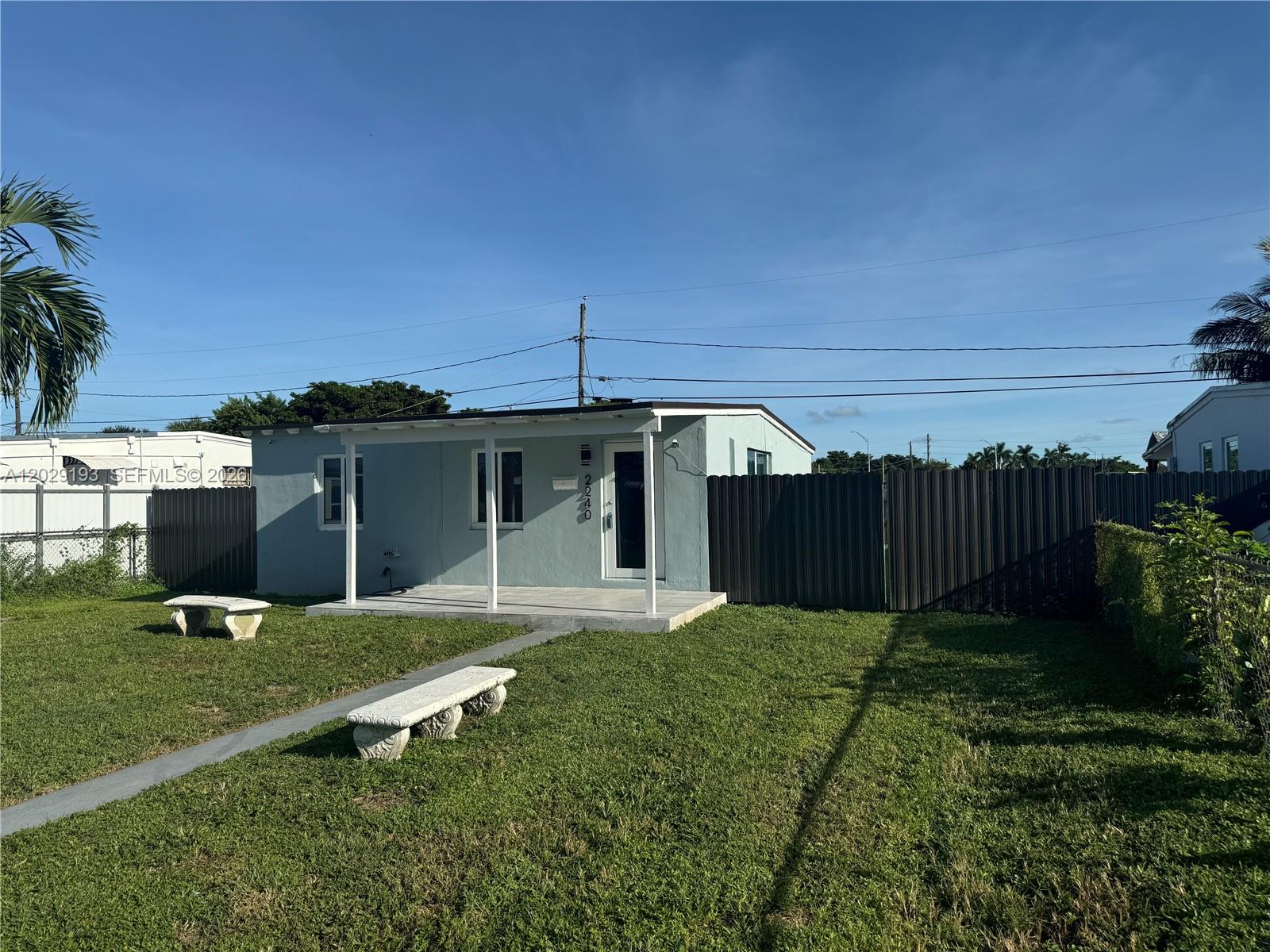 A light blue single-story house features a covered front porch and a dark privacy fence — 2240 Rutland St # 0, Opa-Locka FL 33054, OPA-LOCKA, FL