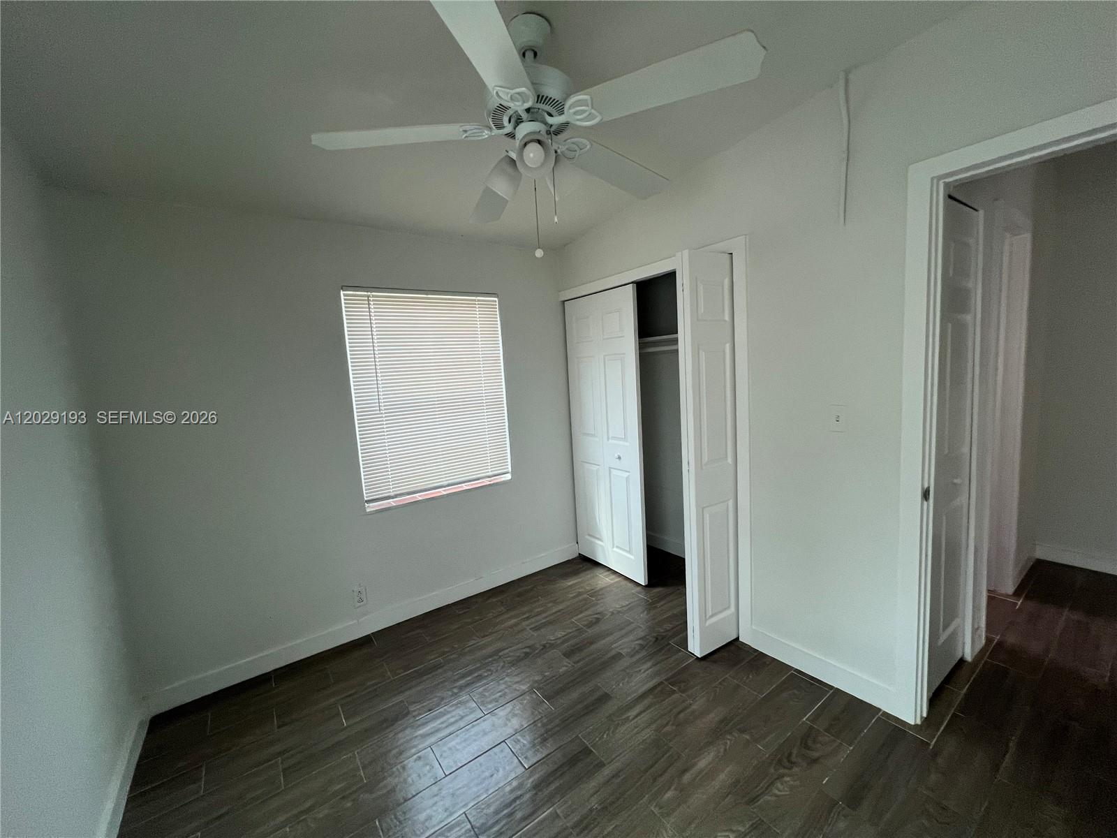 A bedroom features white walls, dark wood-look tile flooring, a ceiling fan, and a closet — 2240 Rutland St # 0, Opa-Locka FL 33054, OPA-LOCKA, FL