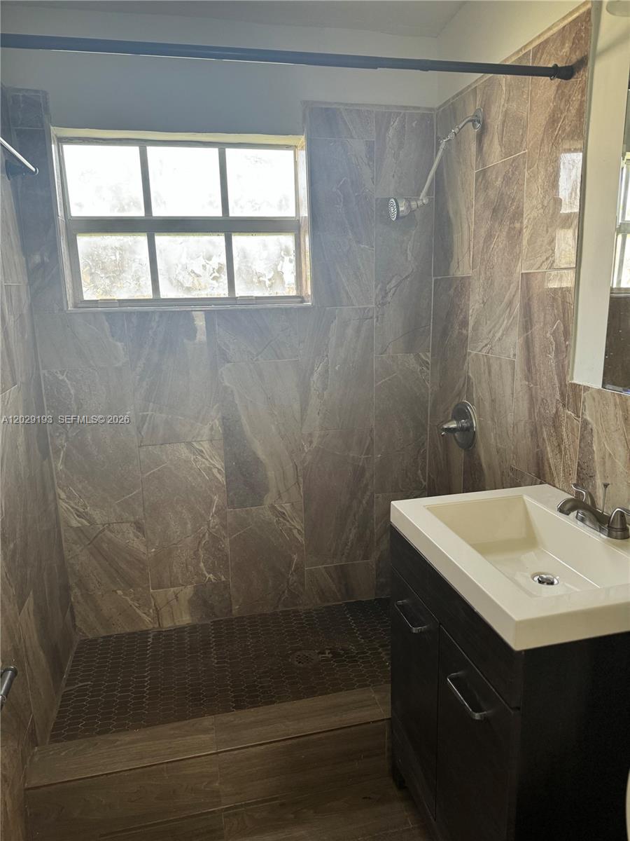 A bathroom features a tiled walk-in shower, a dark wood vanity, and a window — 2240 Rutland St # 0, Opa-Locka FL 33054, OPA-LOCKA, FL