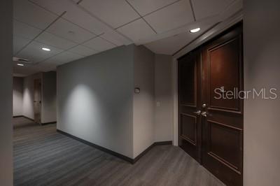 A hallway with gray flooring leads to a set of dark wood double doors — 449 S 12TH STREET UNIT 2401, TAMPA, FL