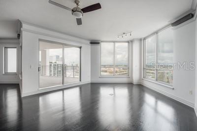A bright living room with dark hardwood floors, a ceiling fan, and floor-to-ceiling windows — 449 S 12TH STREET UNIT 2401, TAMPA, FL