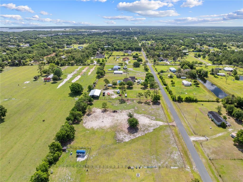 An aerial view shows a rural property with a house, outbuildings, and fenced pastures — HUNTING LODGE DRIVE, ST CLOUD, FL