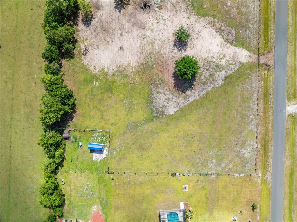 An aerial view shows a fenced grassy lot with a small shed and scattered trees — HUNTING LODGE DRIVE, ST CLOUD, FL