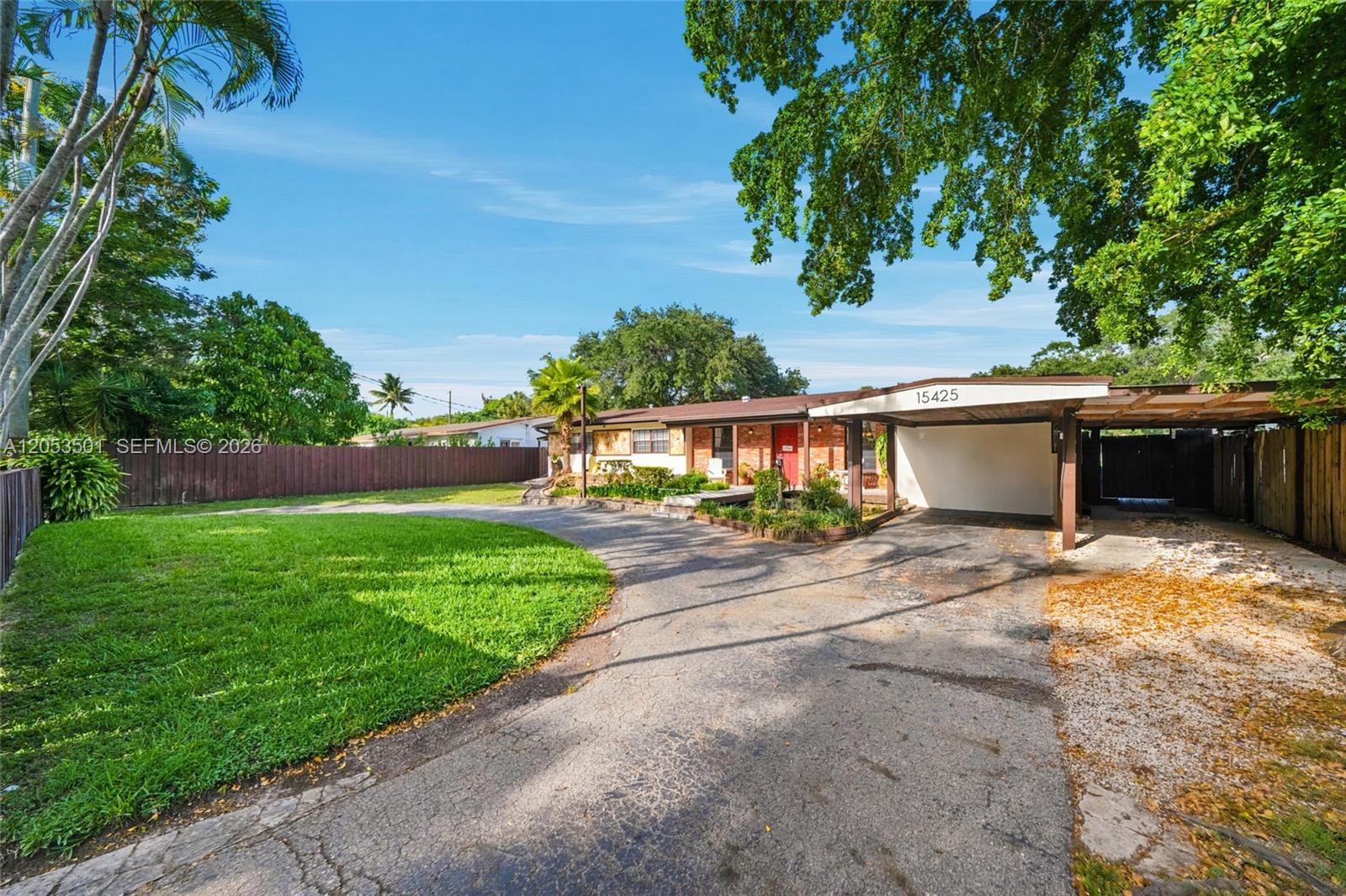 A single-story house with a carport and a large circular driveway sits on a lawn — 15425 N Miami Ave, Miami FL 33169, MIAMI, FL