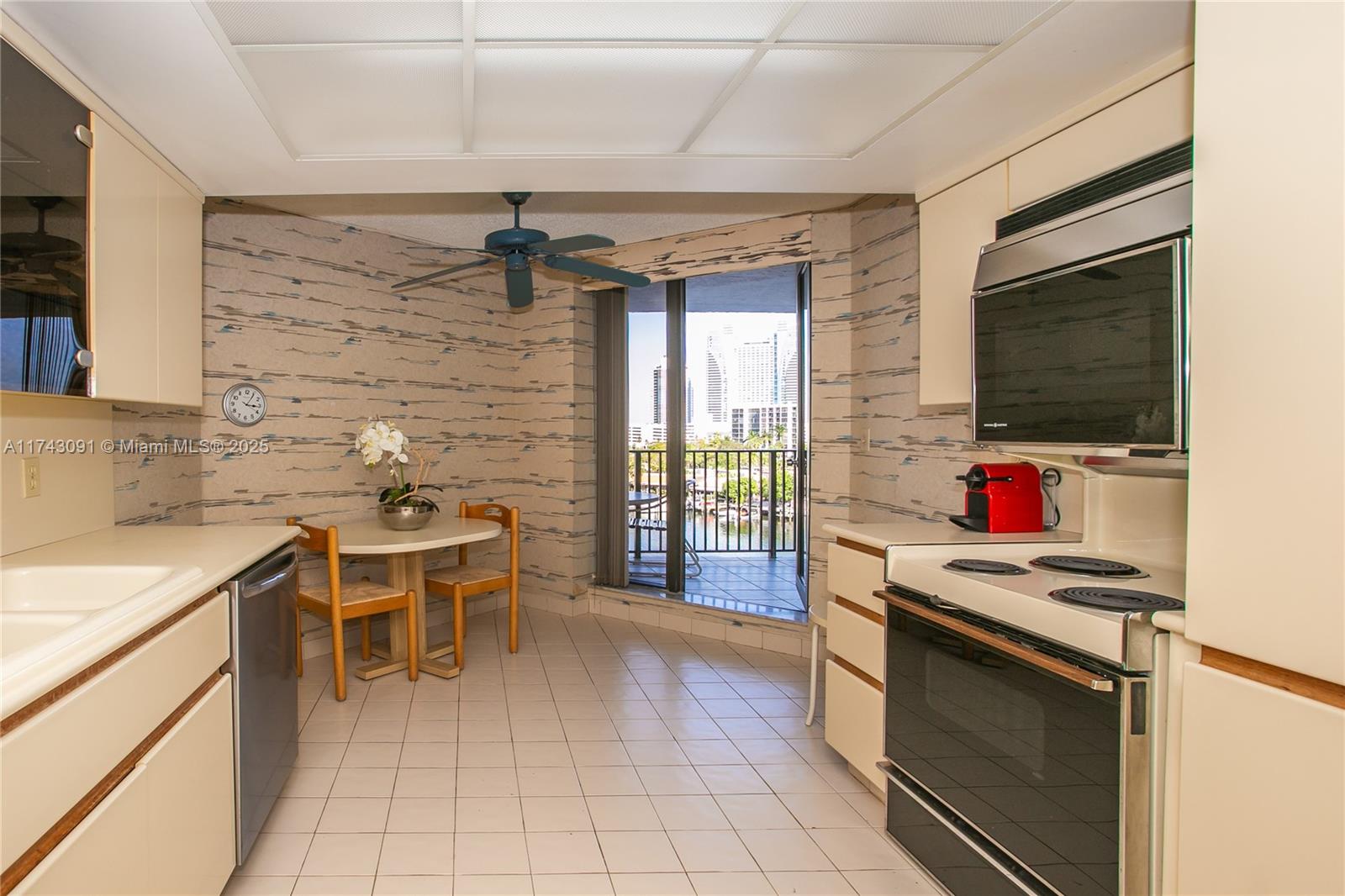 A kitchen features white cabinets, tile flooring, a dining nook, and a balcony with city views — 300 Three Islands Blvd # 406, Hallandale Beach FL 33009, HALLANDALE BEACH, FL