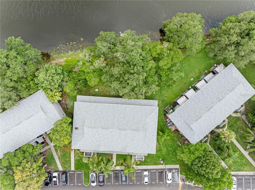 An aerial view shows three apartment buildings surrounded by trees and a parking lot — 7200 E BANK DRIVE UNIT 0, TAMPA, FL