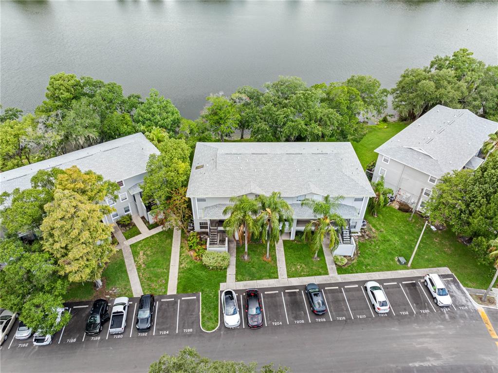 An aerial view shows two apartment buildings with a parking lot in front and a lake — 7200 E BANK DRIVE UNIT 0, TAMPA, FL