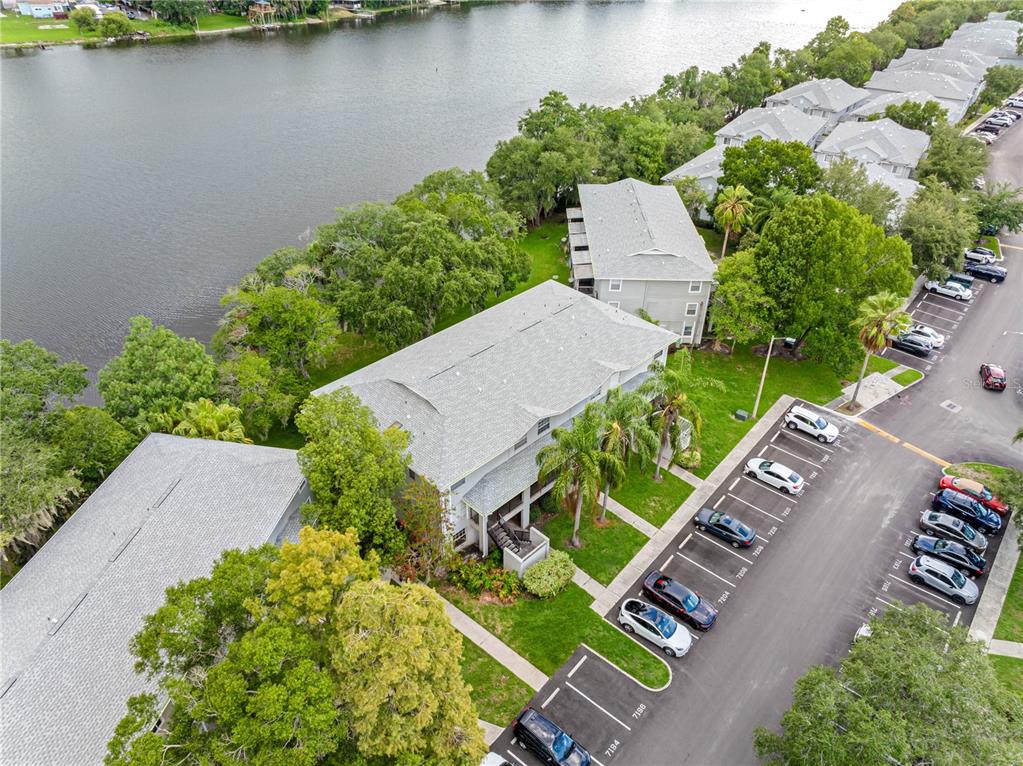 An aerial view shows apartment buildings situated along a lake with adjacent parking lots — 7200 E BANK DRIVE UNIT 0, TAMPA, FL