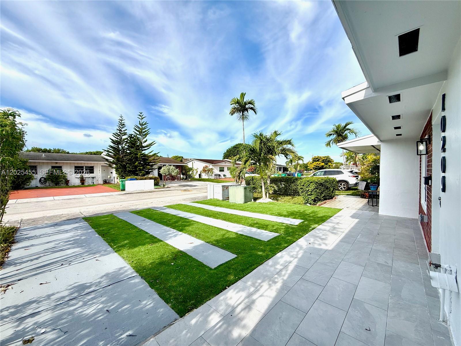 A paved walkway leads to a house entrance with a lawn featuring concrete strips — 10209 SW 20th Ter, Miami FL 33165, MIAMI, FL