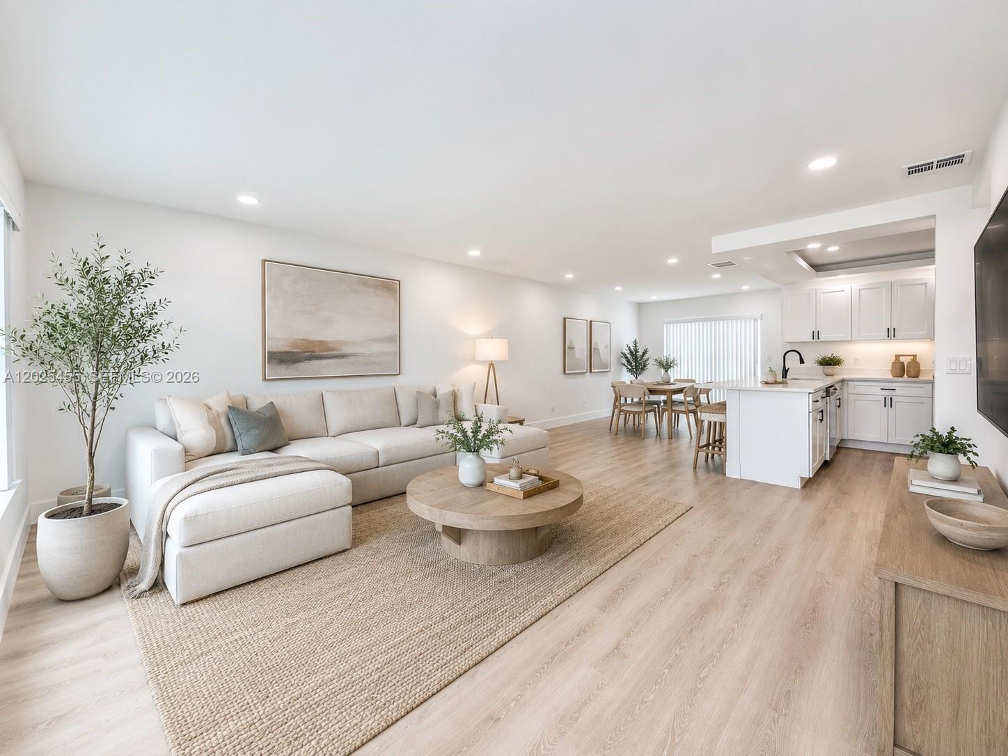 An open-concept living room and kitchen feature light wood flooring, a sectional sofa, and cabinetry — 10209 SW 20th Ter, Miami FL 33165, MIAMI, FL