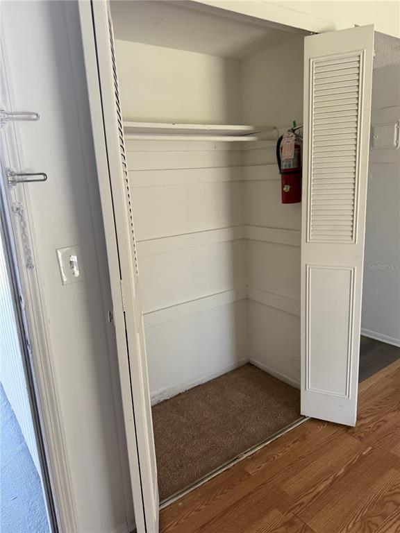 A small closet with a single shelf, a hanging rod, and a wall-mounted fire extinguisher — 5317 CURRY FORD ROAD UNIT 103, ORLANDO, FL
