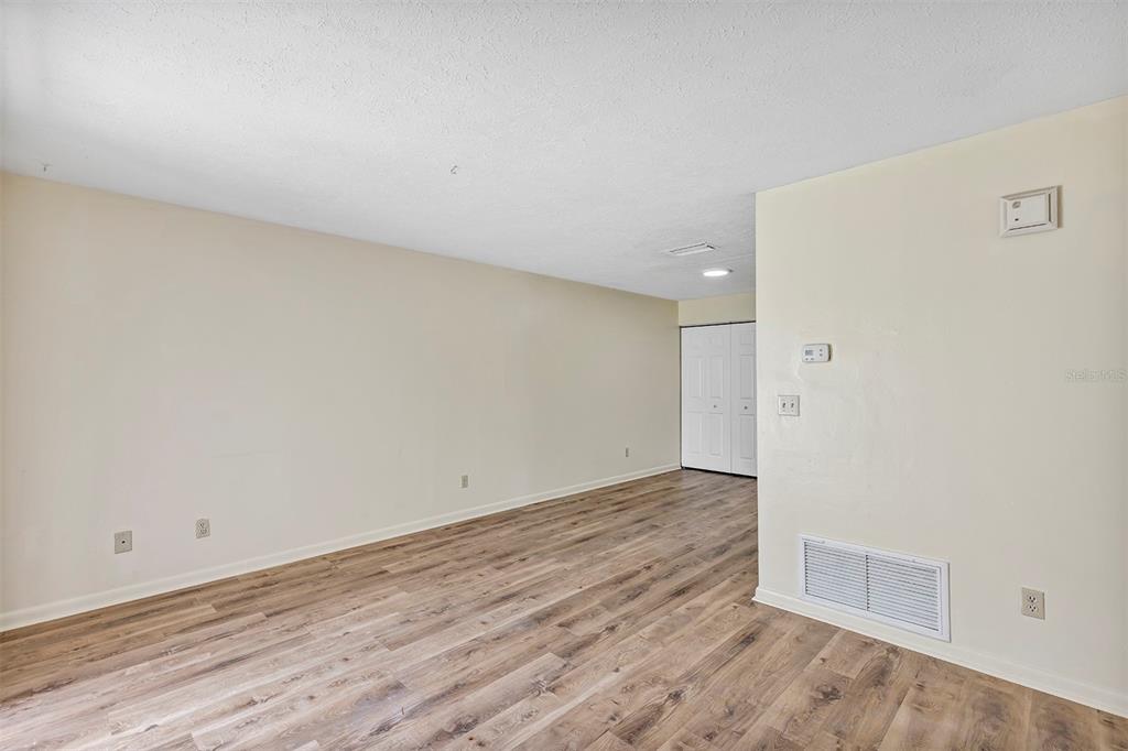 An empty room with light-colored walls, wood-look flooring, and a white closet door — 3800 SE 17TH CT UNIT C, OCALA, FL