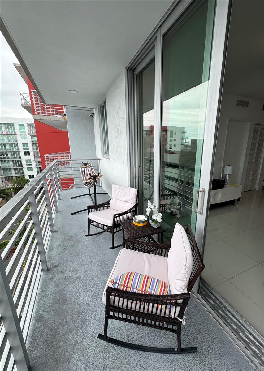 A balcony features two rocking chairs, a small side table, and a metal railing — 7875 NW 107th Ave # 602, Doral FL 33178, DORAL, FL