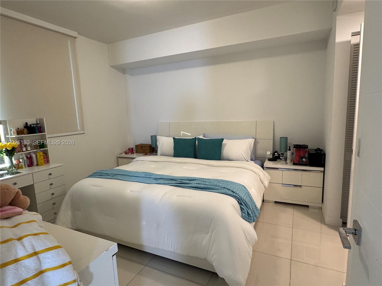 A bedroom features a white bed with teal accents, matching nightstands, and a white vanity — 7875 NW 107th Ave # 602, Doral FL 33178, DORAL, FL