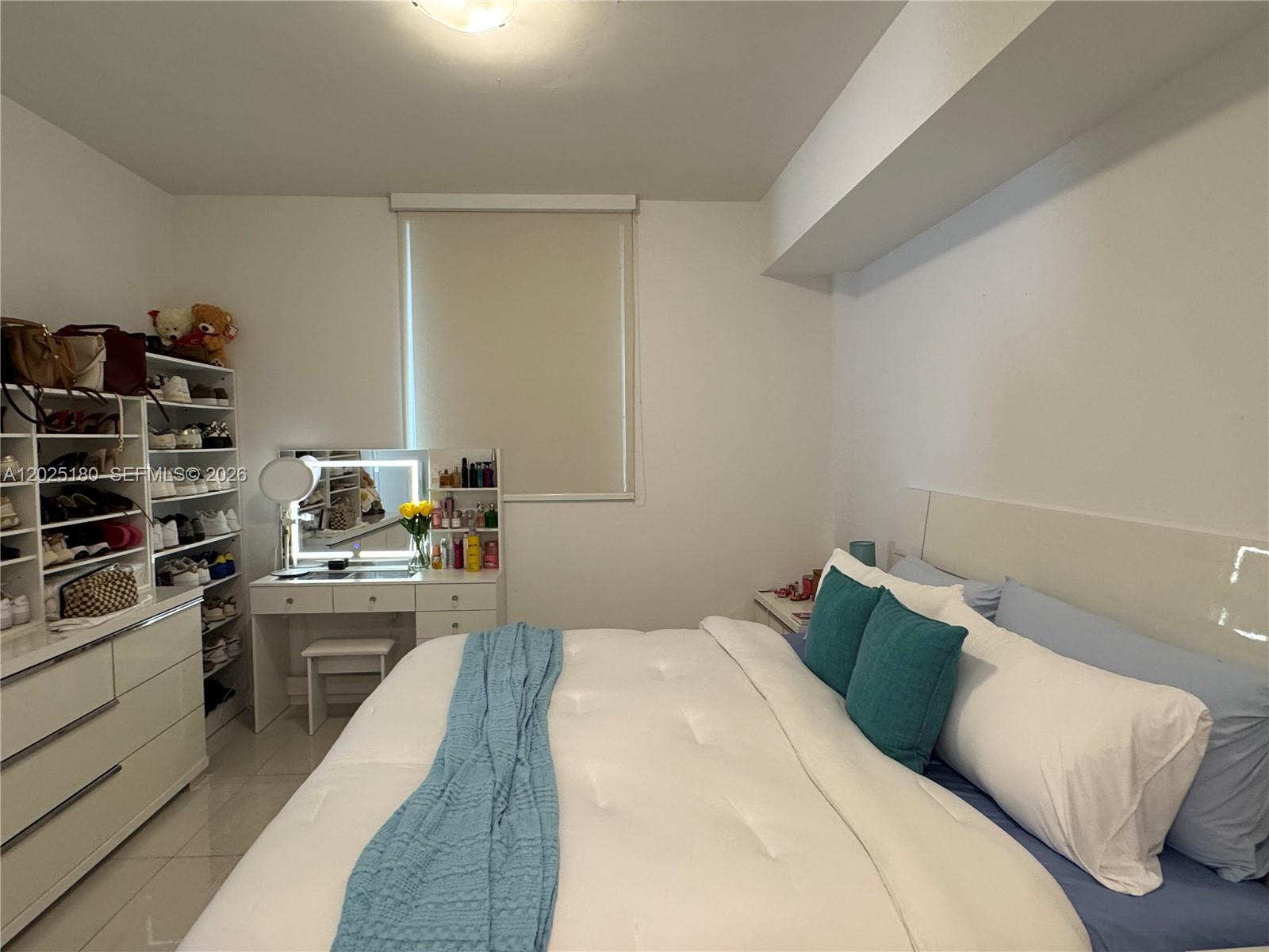 A bedroom features a white bed, a vanity with a mirror, and open shelving units — 7875 NW 107th Ave # 602, Doral FL 33178, DORAL, FL