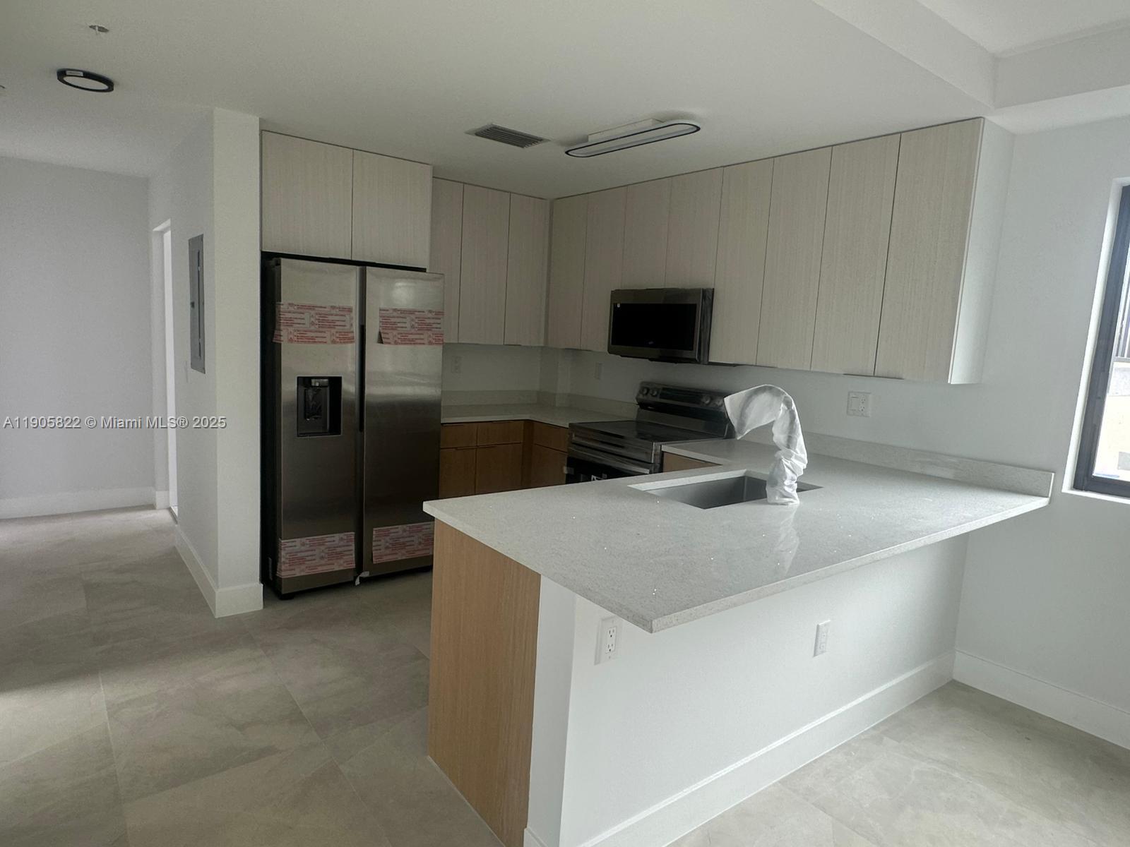 A modern kitchen features light wood cabinetry, stainless steel appliances, and a white quartz countertop — 5423 NE Miami Ct # 7, Miami FL 33137, MIAMI, FL