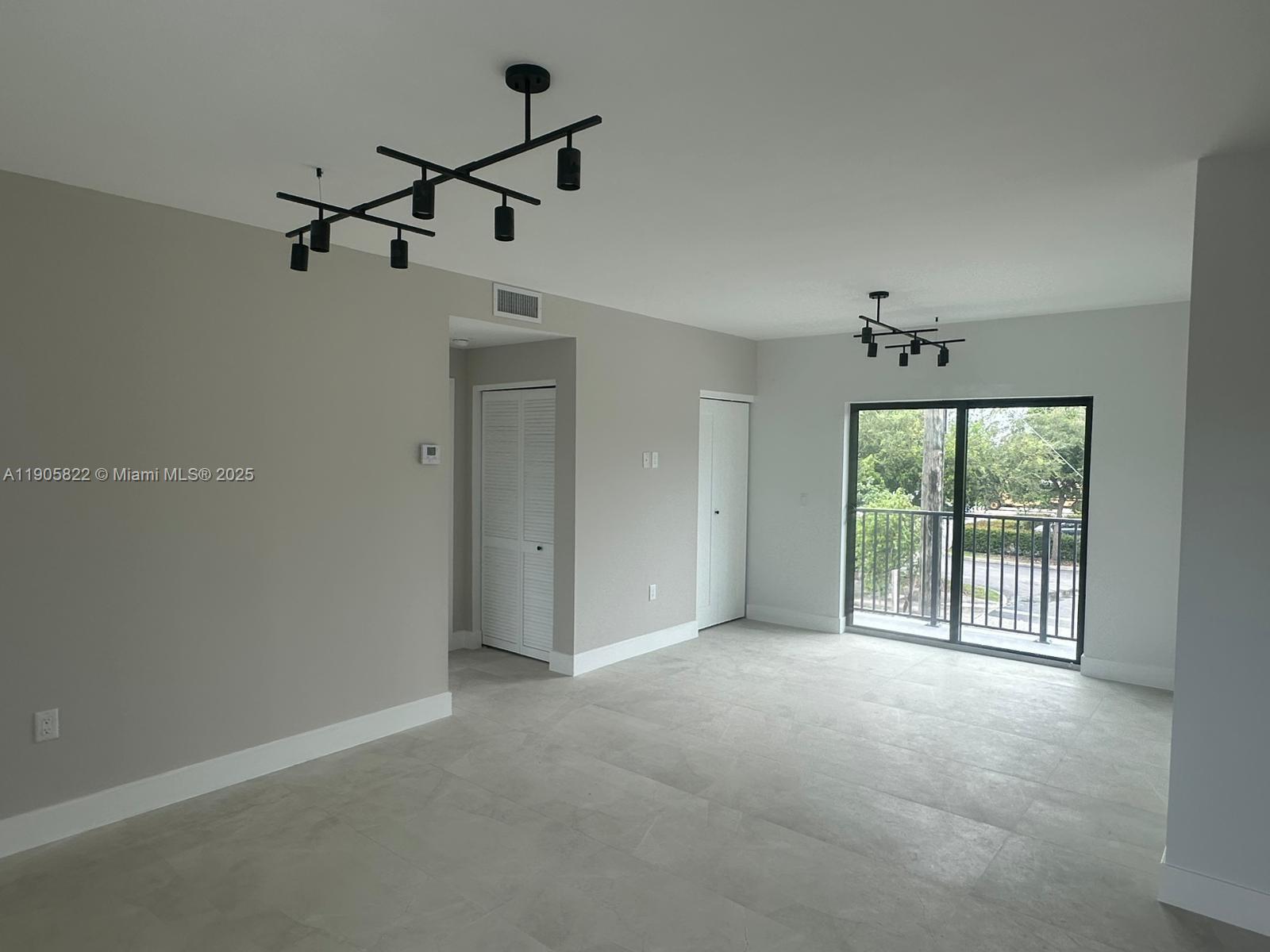 A living area features light gray tile floors, two modern black chandeliers, and a balcony — 5423 NE Miami Ct # 7, Miami FL 33137, MIAMI, FL