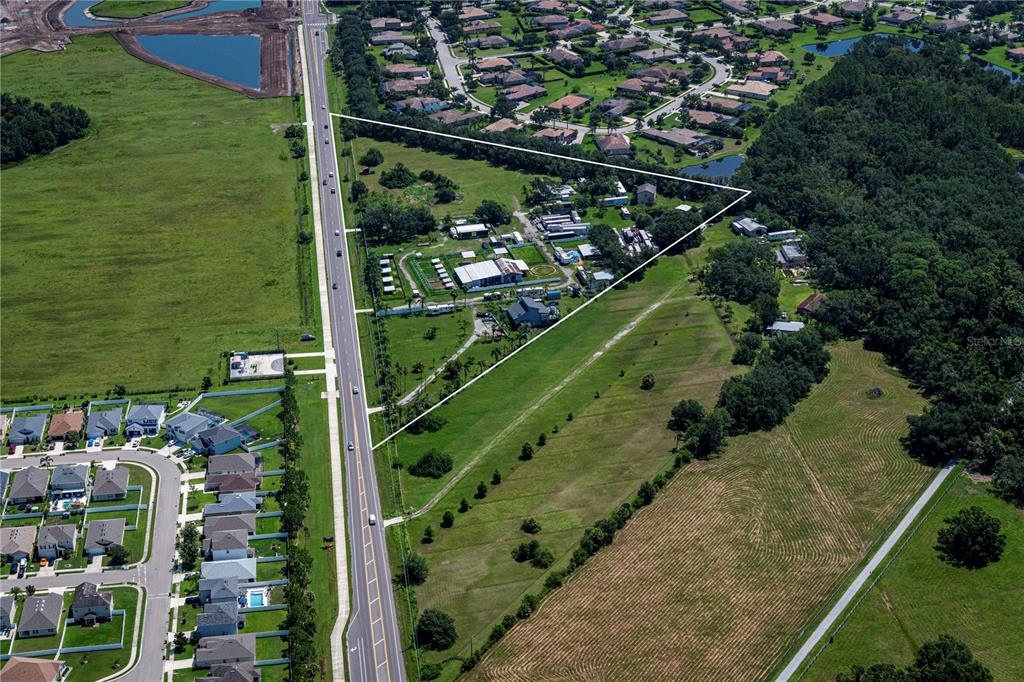 An aerial view shows a triangular parcel of land bordered by a road and trees — 211 RYE ROAD NE, BRADENTON, FL