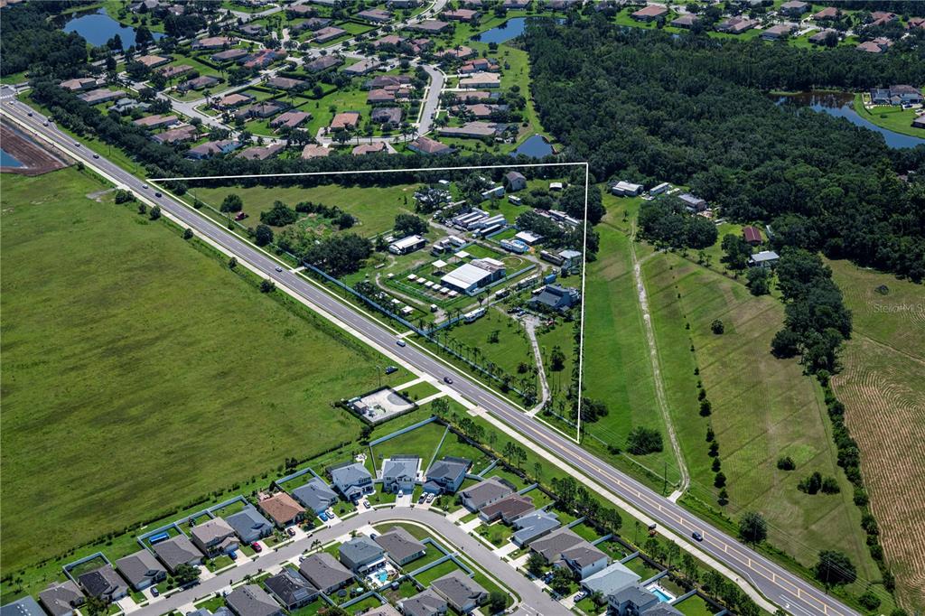 An aerial view shows a triangular property with several buildings situated next to a road — 211 RYE ROAD NE, BRADENTON, FL