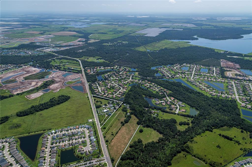 An aerial view shows a triangular parcel of land highlighted amidst suburban neighborhoods and fields — 211 RYE ROAD NE, BRADENTON, FL