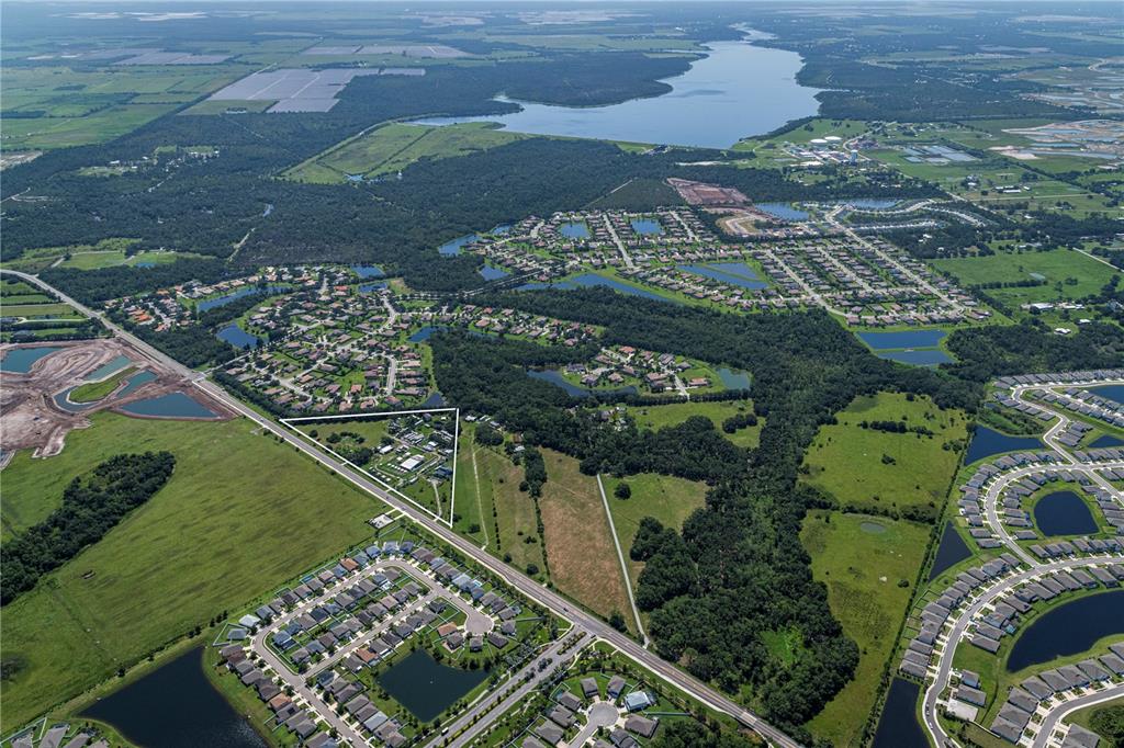 An aerial view shows a triangular property outlined in white amidst suburban developments and greenery — 211 RYE ROAD NE, BRADENTON, FL