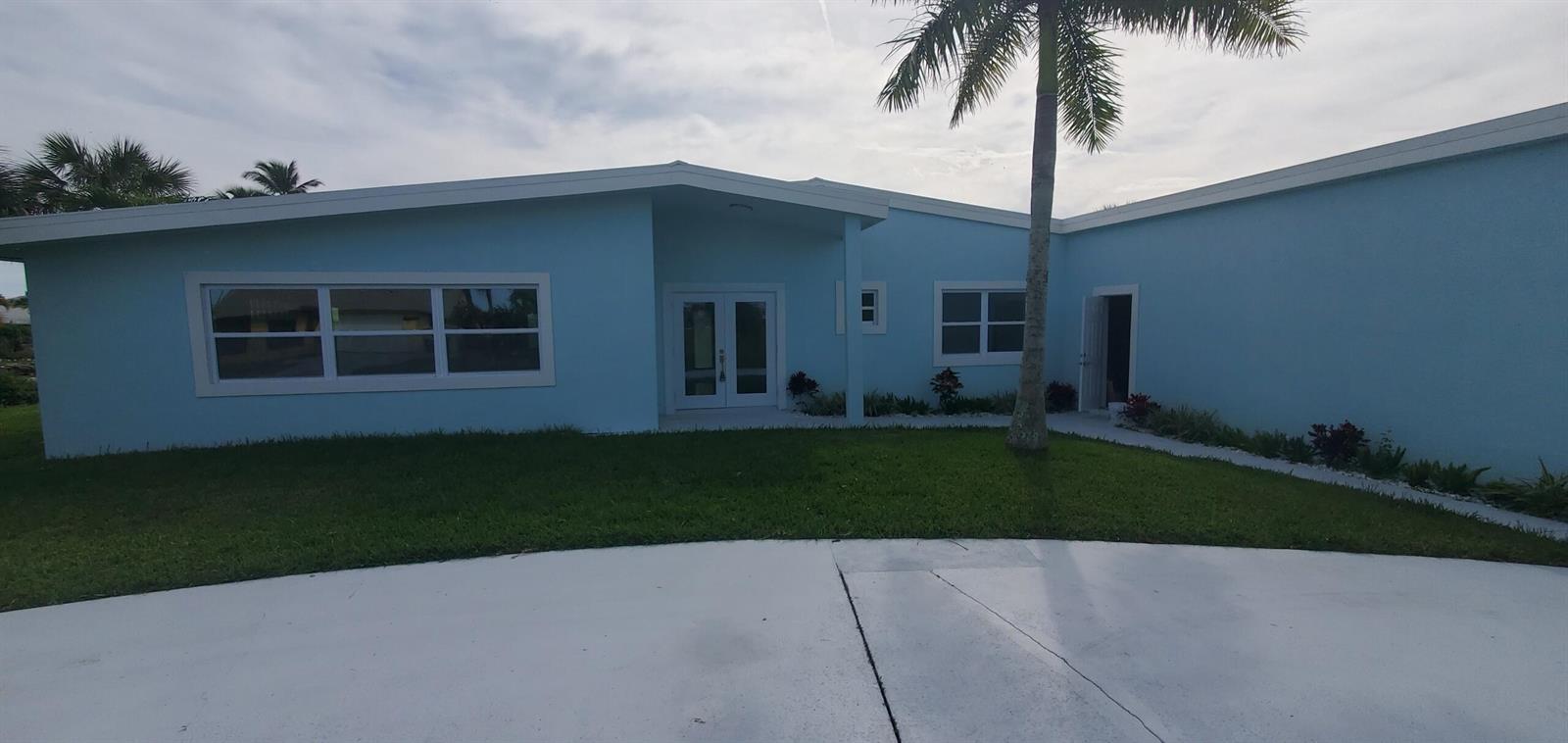 A light blue single-story house with a white roof, double front doors, and a palm tree — 1529 Thumb Point Drive, Fort Pierce FL 34949, FORT PIERCE, FL