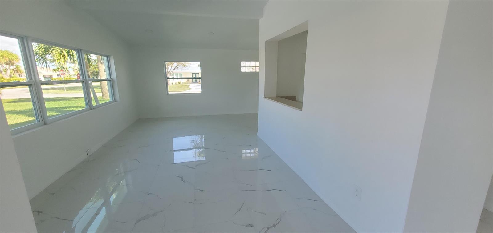 An empty room with white walls, white marble-look tile flooring, and multiple windows — 1529 Thumb Point Drive, Fort Pierce FL 34949, FORT PIERCE, FL