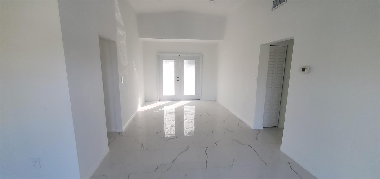 A bright, empty room features white walls, vaulted ceilings, and white marble-patterned tile flooring — 1529 Thumb Point Drive, Fort Pierce FL 34949, FORT PIERCE, FL