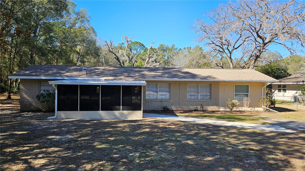 A single-story brick house with a screened-in porch and a light-colored shingled roof — 662 N CHARLES AVENUE, INVERNESS, FL